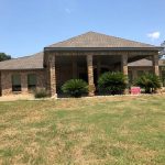 Beautiful brick house with a covered porch and lush landscaping.