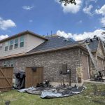 Roof repair work on a residential house with a ladder and roofing materials.